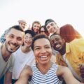 A diverse group of friends taking a joyful selfie outdoors during sunset.